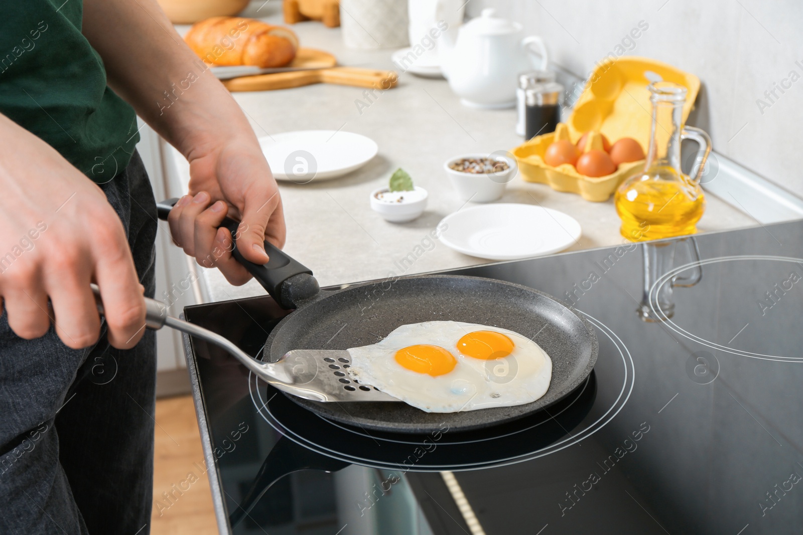 Photo of Man taking fried eggs from frying pan in kitchen, closeup