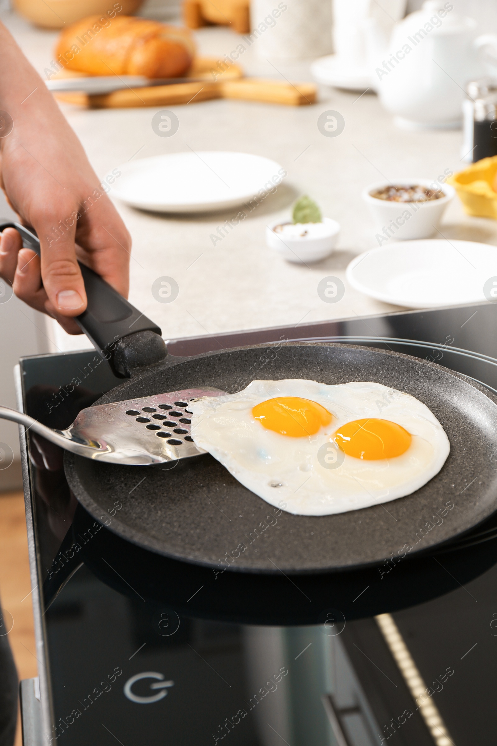 Photo of Man taking fried eggs from frying pan in kitchen, closeup