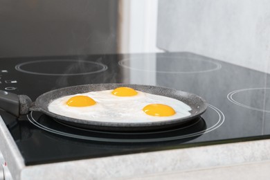 Photo of Cooking tasty eggs on frying pan in kitchen, closeup