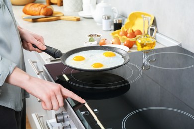 Photo of Woman cooking eggs in frying pan on cooktop indoors, closeup