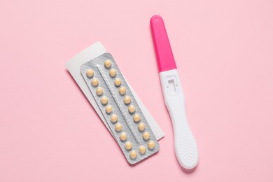 Photo of Blister of oral contraceptive pills and pregnancy test on pink background, flat lay