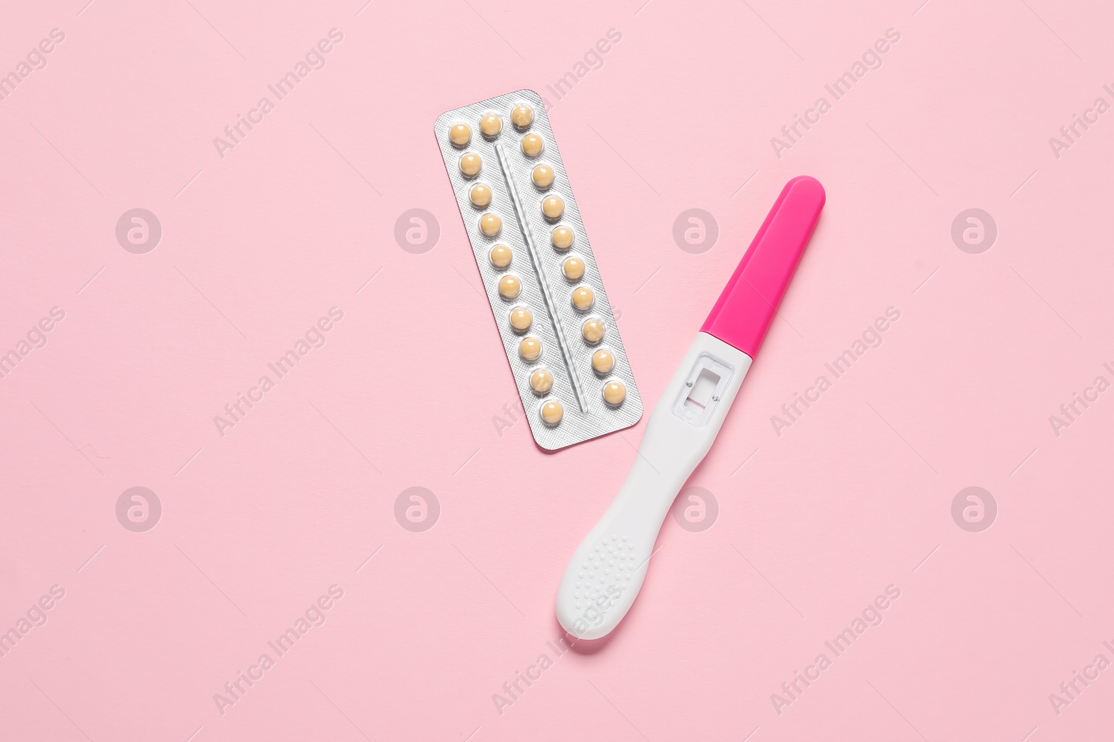 Photo of Blister of oral contraceptive pills and pregnancy test on pink background, flat lay