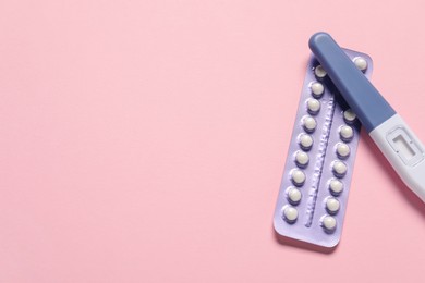 Photo of Blister of oral contraceptive pills and pregnancy test on pink background, flat lay. Space for text