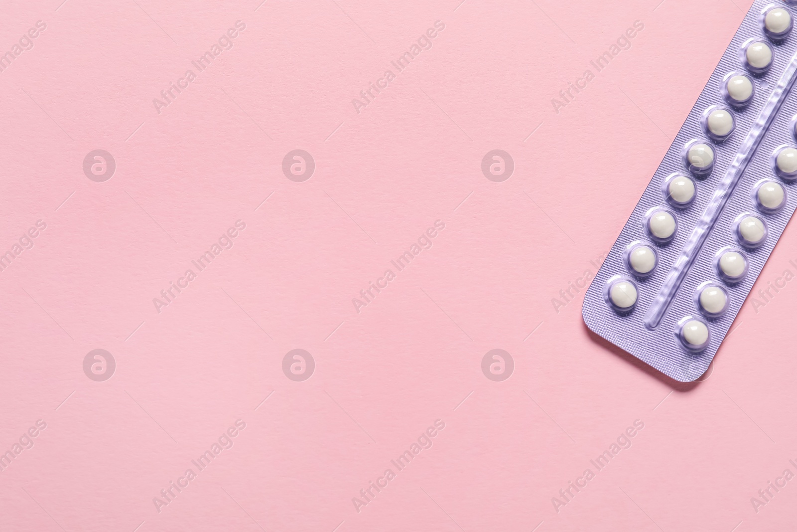 Photo of Blister of oral contraceptive pills on pink background, top view. Space for text