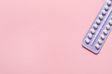 Photo of Blister of oral contraceptive pills on pink background, top view. Space for text