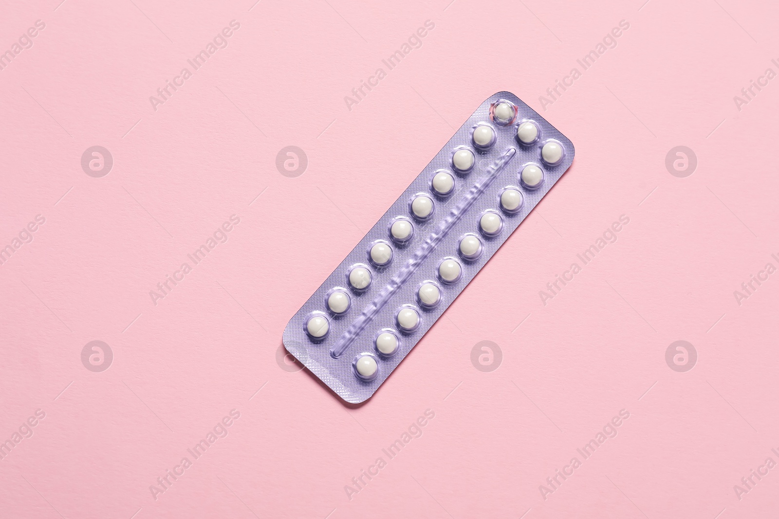 Photo of Blister of oral contraceptive pills on pink background, top view