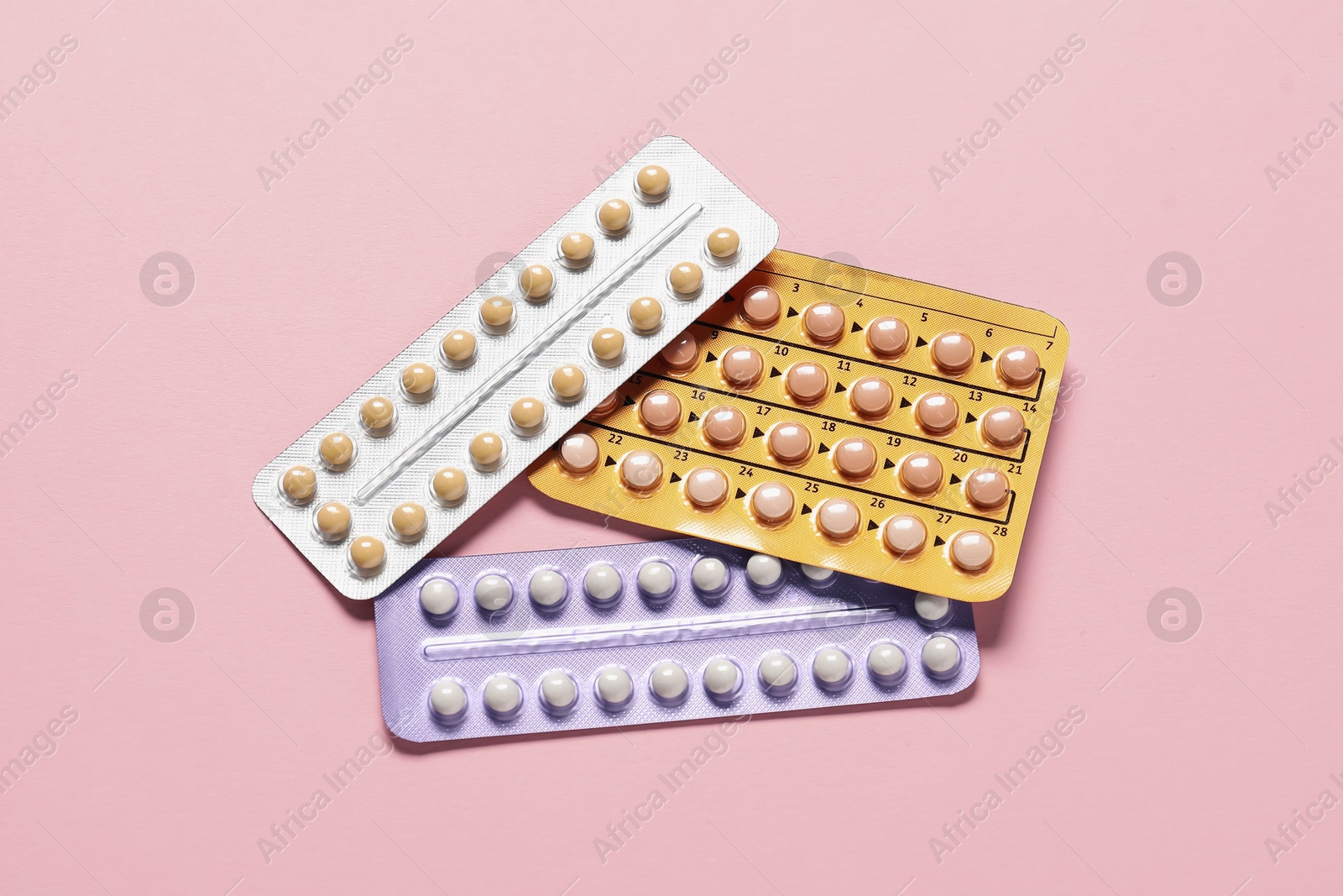 Photo of Blisters of oral contraceptive pills on pink background, flat lay