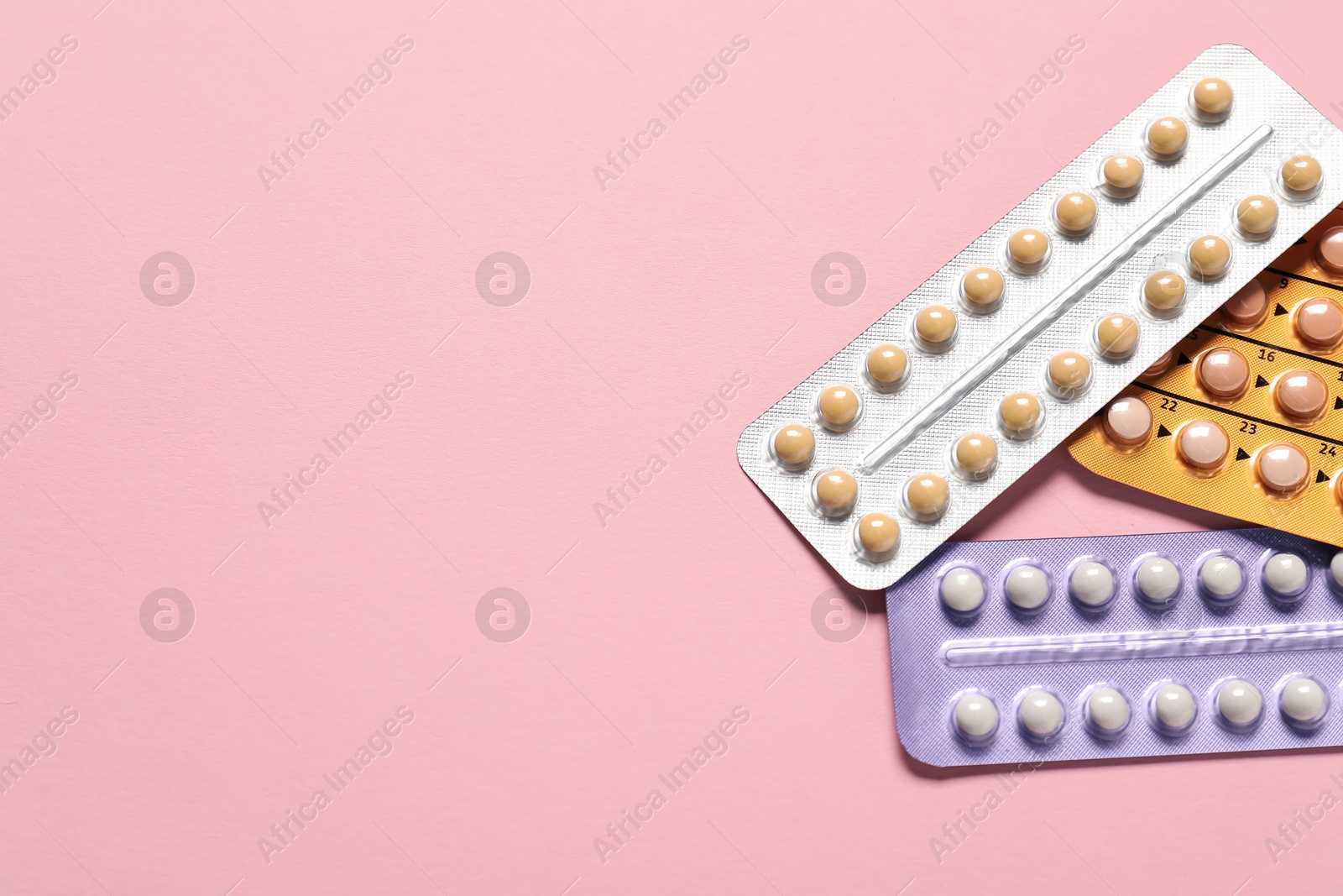 Photo of Blisters of oral contraceptive pills on pink background, flat lay. Space for text