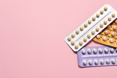 Photo of Blisters of oral contraceptive pills on pink background, flat lay. Space for text