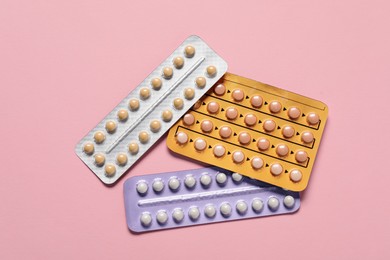 Photo of Blisters of oral contraceptive pills on pink background, flat lay