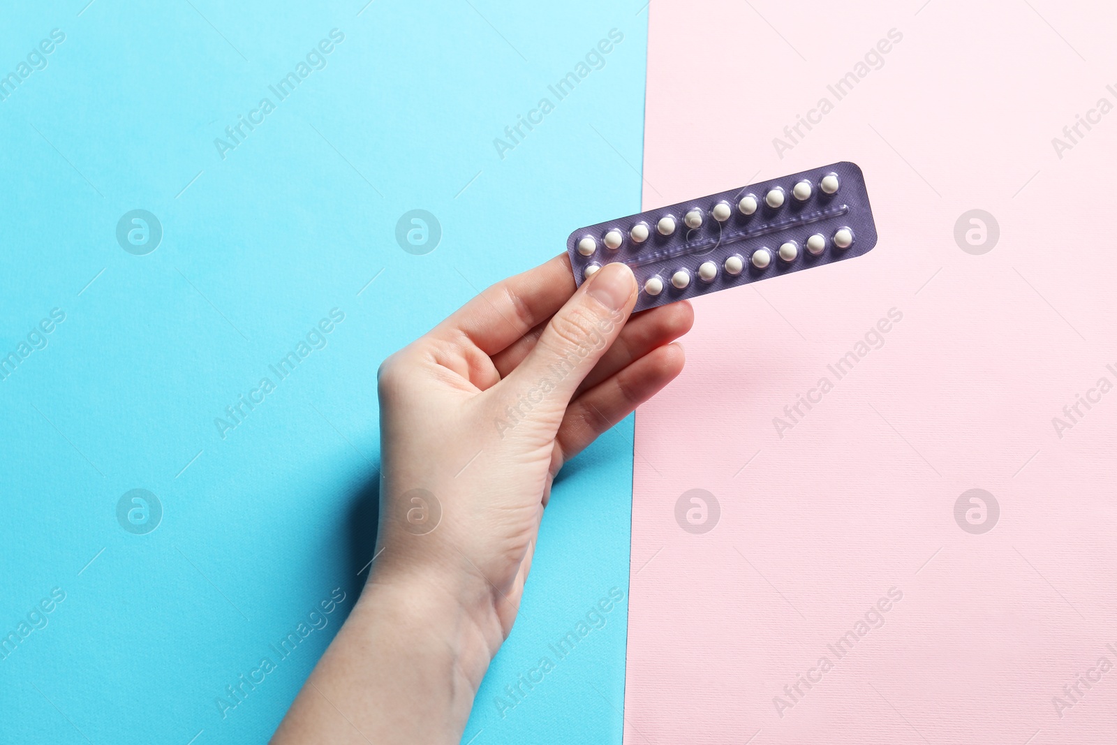 Photo of Woman holding blister of contraceptive pills on color background, closeup