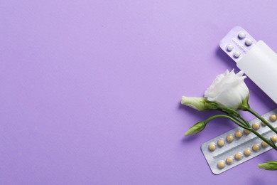 Blisters of contraceptive pills and eustoma flowers on lilac background, flat lay. Space for text