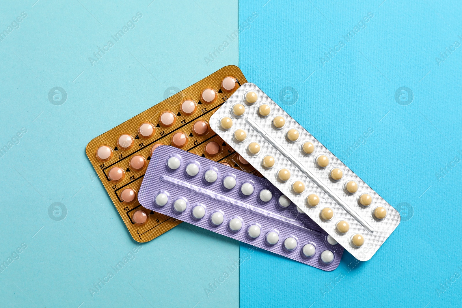 Photo of Blisters of contraceptive pills on light blue background, top view