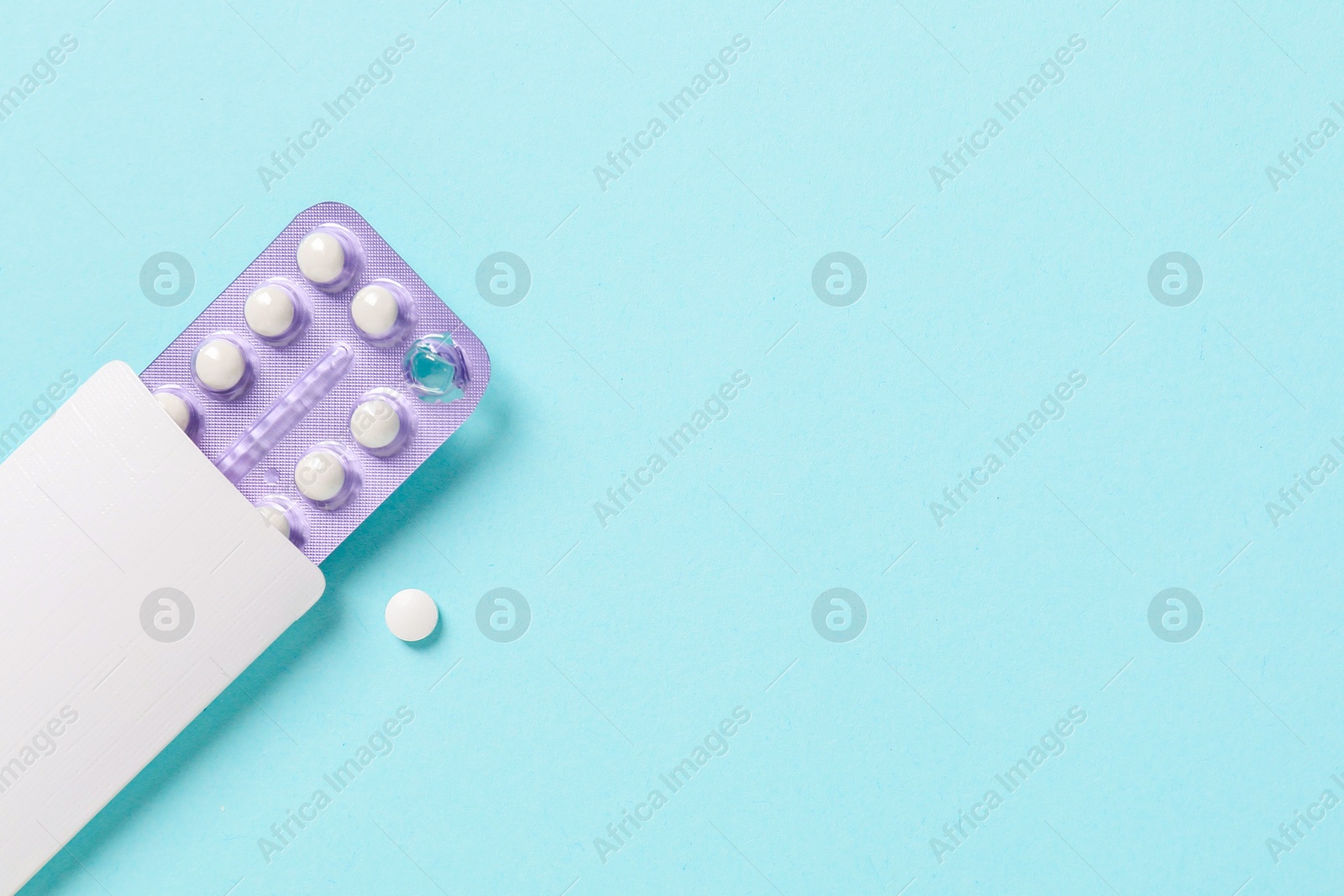 Photo of Blister of contraceptive pills in package on light blue background, top view. Space for text