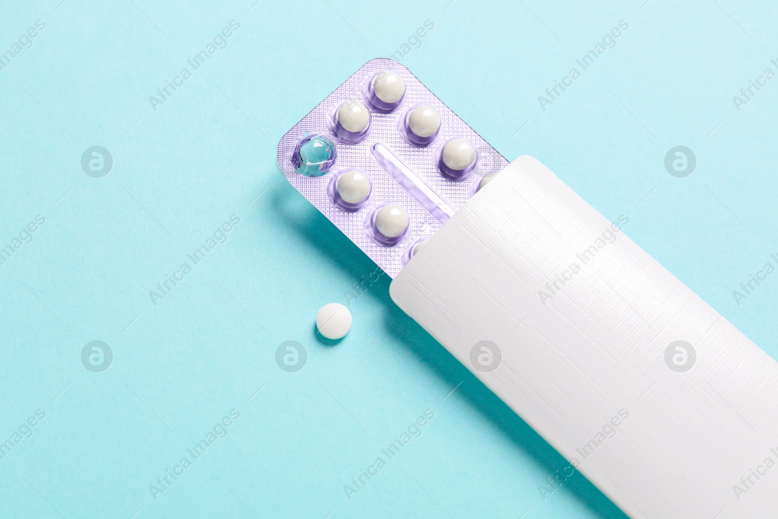 Photo of Blister of contraceptive pills in package on light blue background. Mockup for design