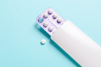 Photo of Blister of contraceptive pills in package on light blue background. Mockup for design