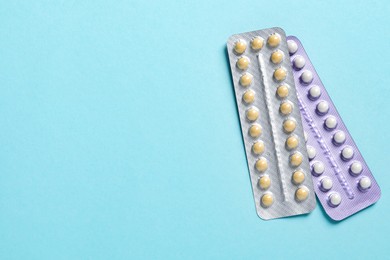 Photo of Blisters of contraceptive pills on light blue background, top view. Space for text