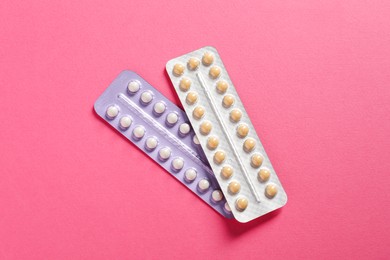 Photo of Blisters of contraceptive pills on pink background, top view