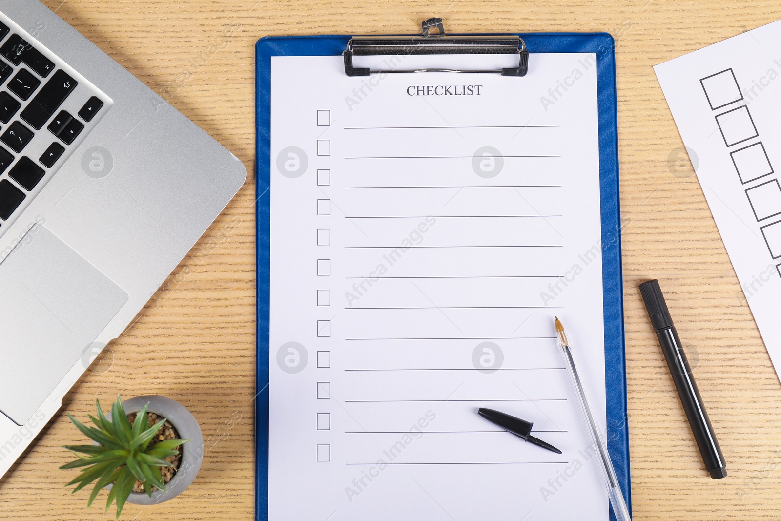 Photo of Checklist with checkboxes, pen, marker, floral decor and laptop on wooden table, flat lay