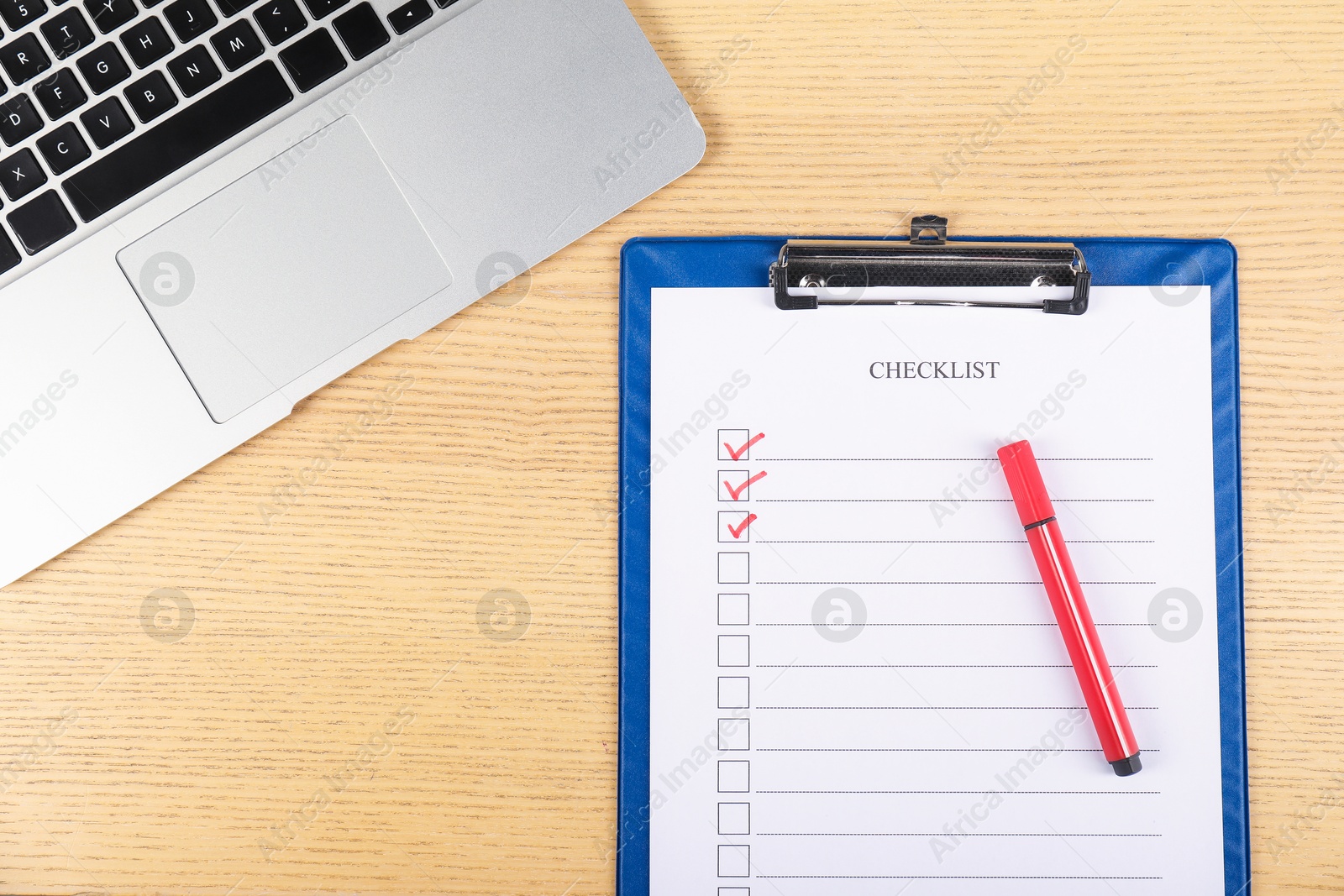 Photo of Checklist with checkboxes, marker and laptop on wooden table, flat lay