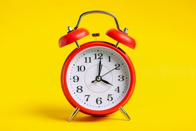 Photo of One red alarm clock on yellow background