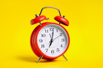 Photo of One red alarm clock on yellow background