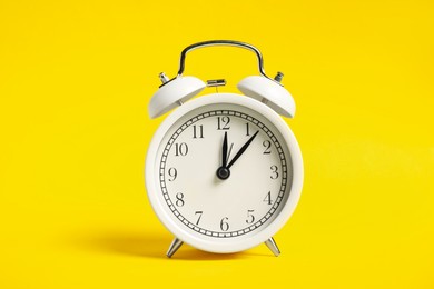 Photo of One white alarm clock on yellow background