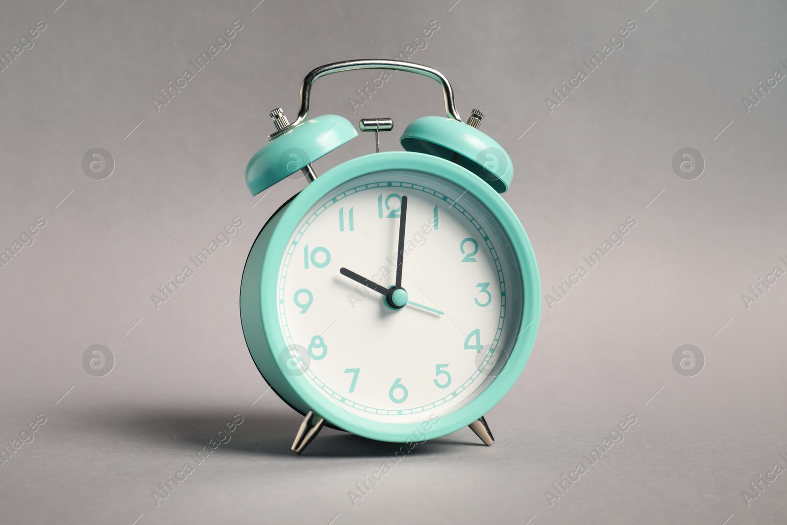 Photo of One turquoise alarm clock on grey background