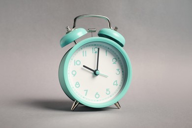 Photo of One turquoise alarm clock on grey background