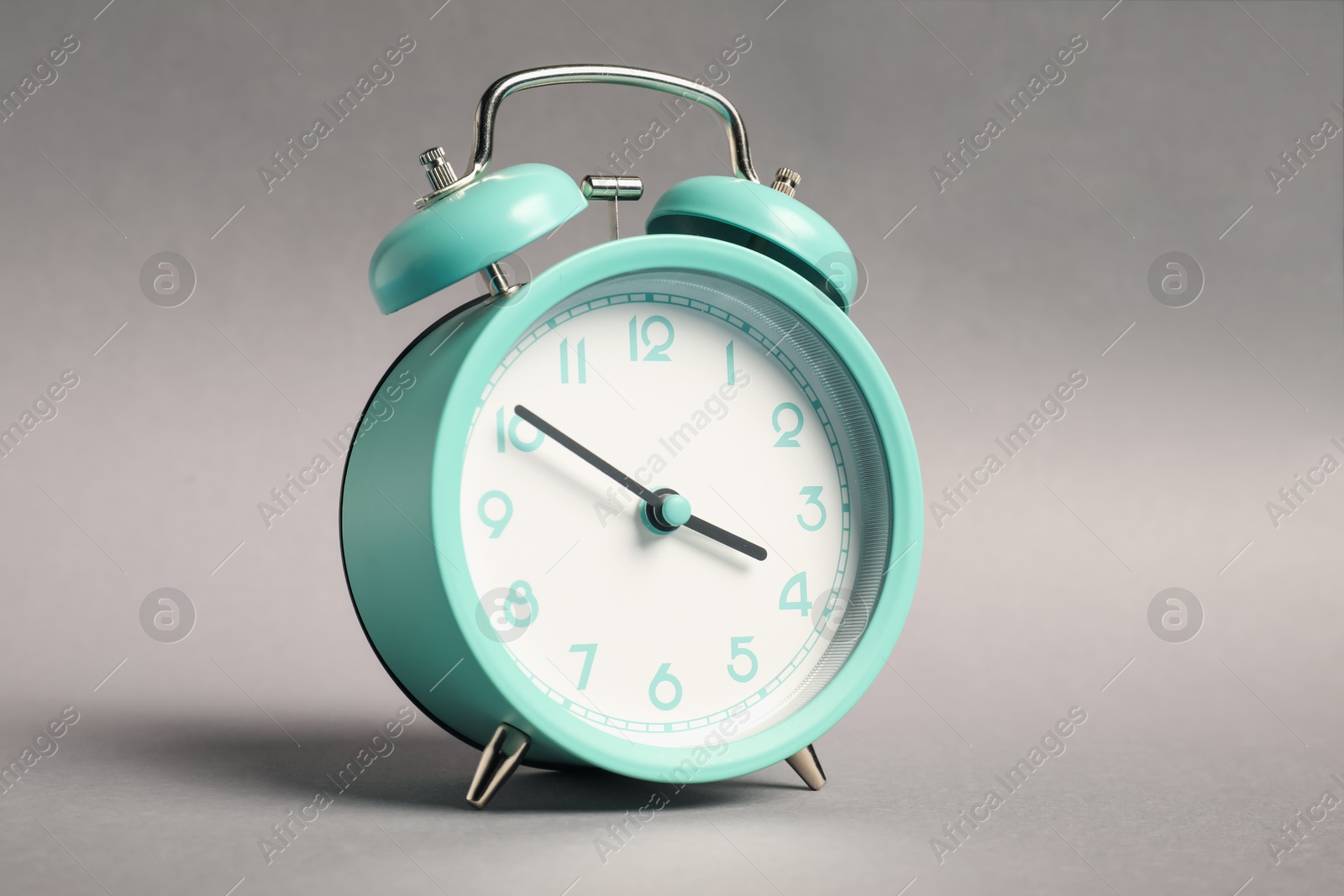 Photo of One turquoise alarm clock on grey background