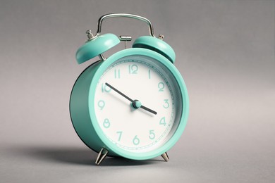 Photo of One turquoise alarm clock on grey background