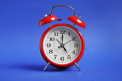Photo of One red alarm clock on blue background