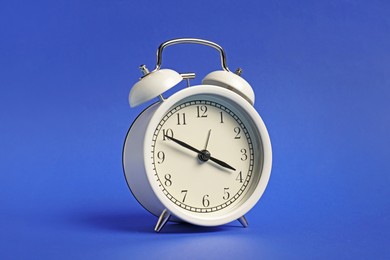 Photo of One white alarm clock on blue background