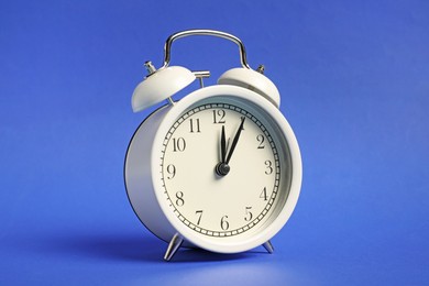 Photo of One white alarm clock on blue background