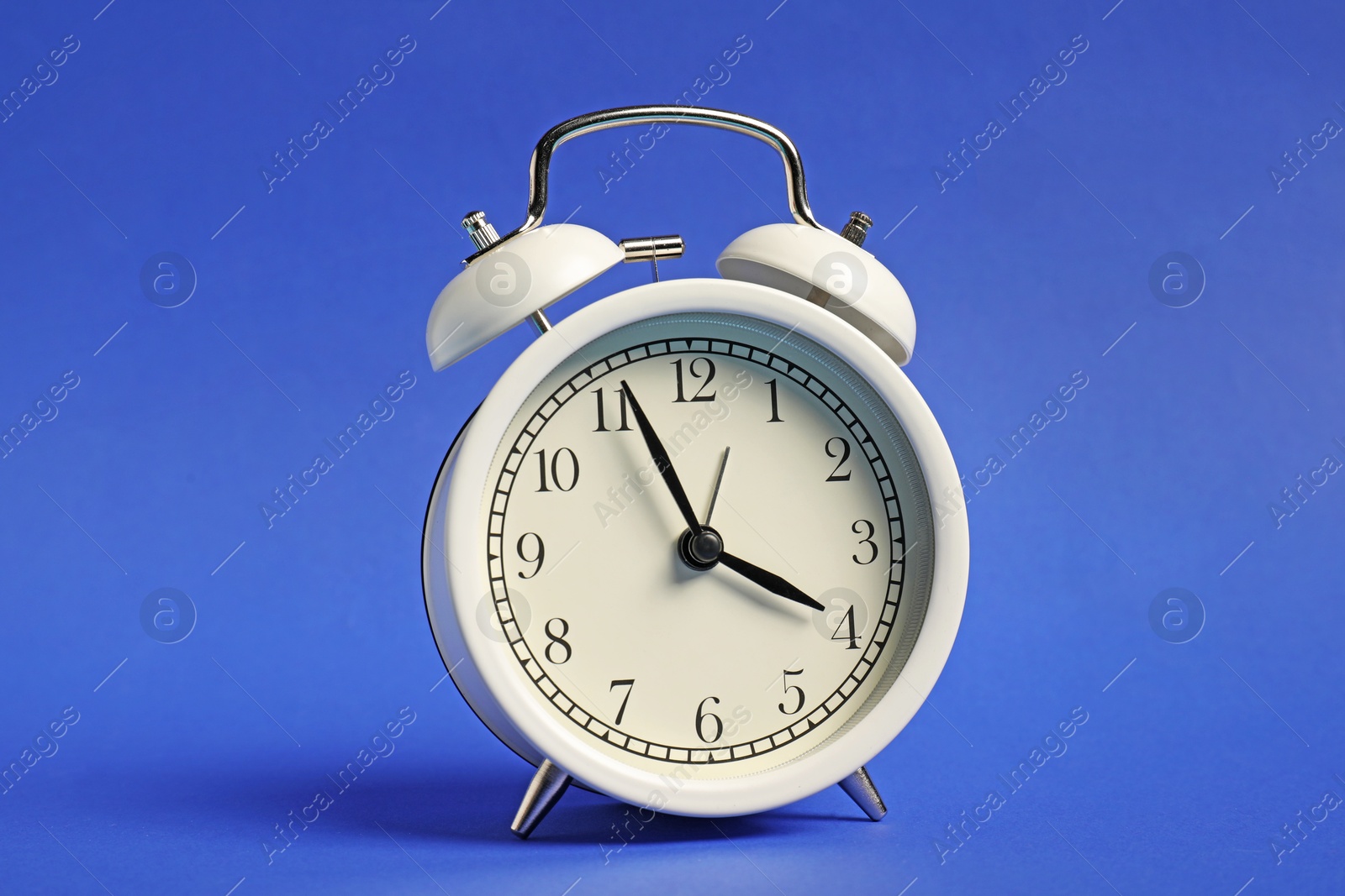 Photo of One white alarm clock on blue background