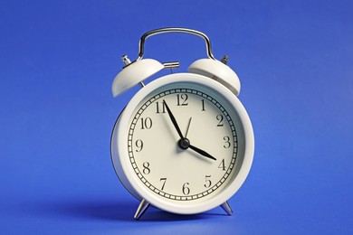 Photo of One white alarm clock on blue background