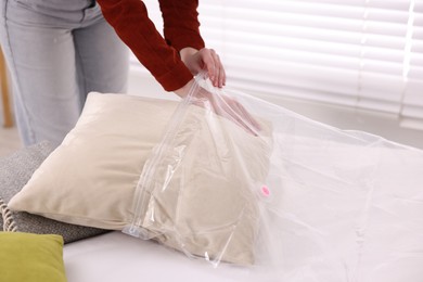 Photo of Woman packing pillow into vacuum bag at home, closeup