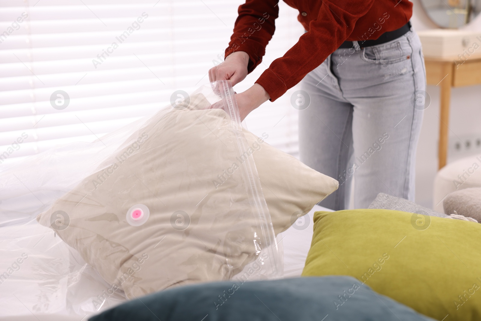 Photo of Woman packing pillow into vacuum bag at home, closeup