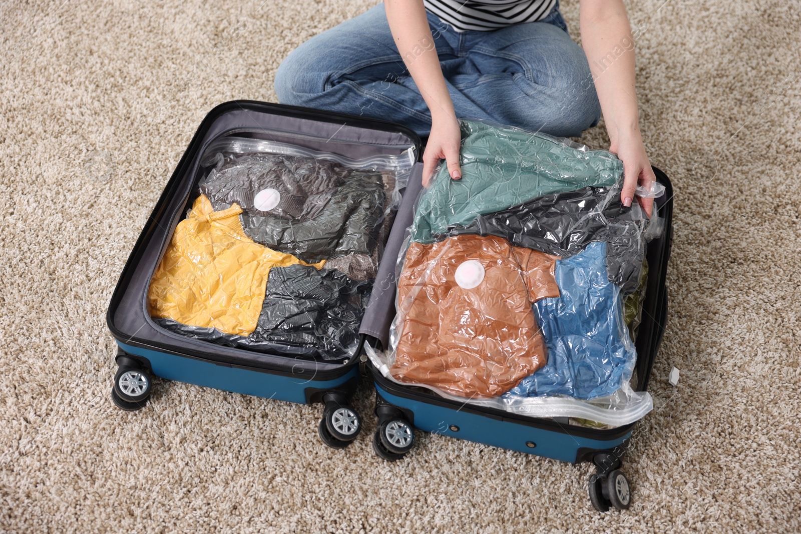 Photo of Woman packing clothes into vacuum bag on floor at home, above view