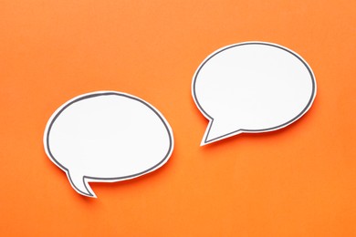 Photo of Blank speech bubbles on orange background, top view. Space for text