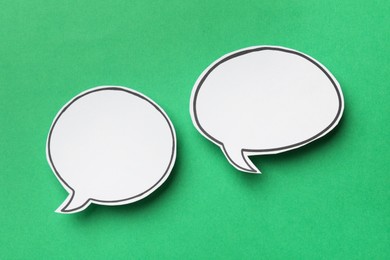 Photo of Blank speech bubbles on green background, top view. Space for text