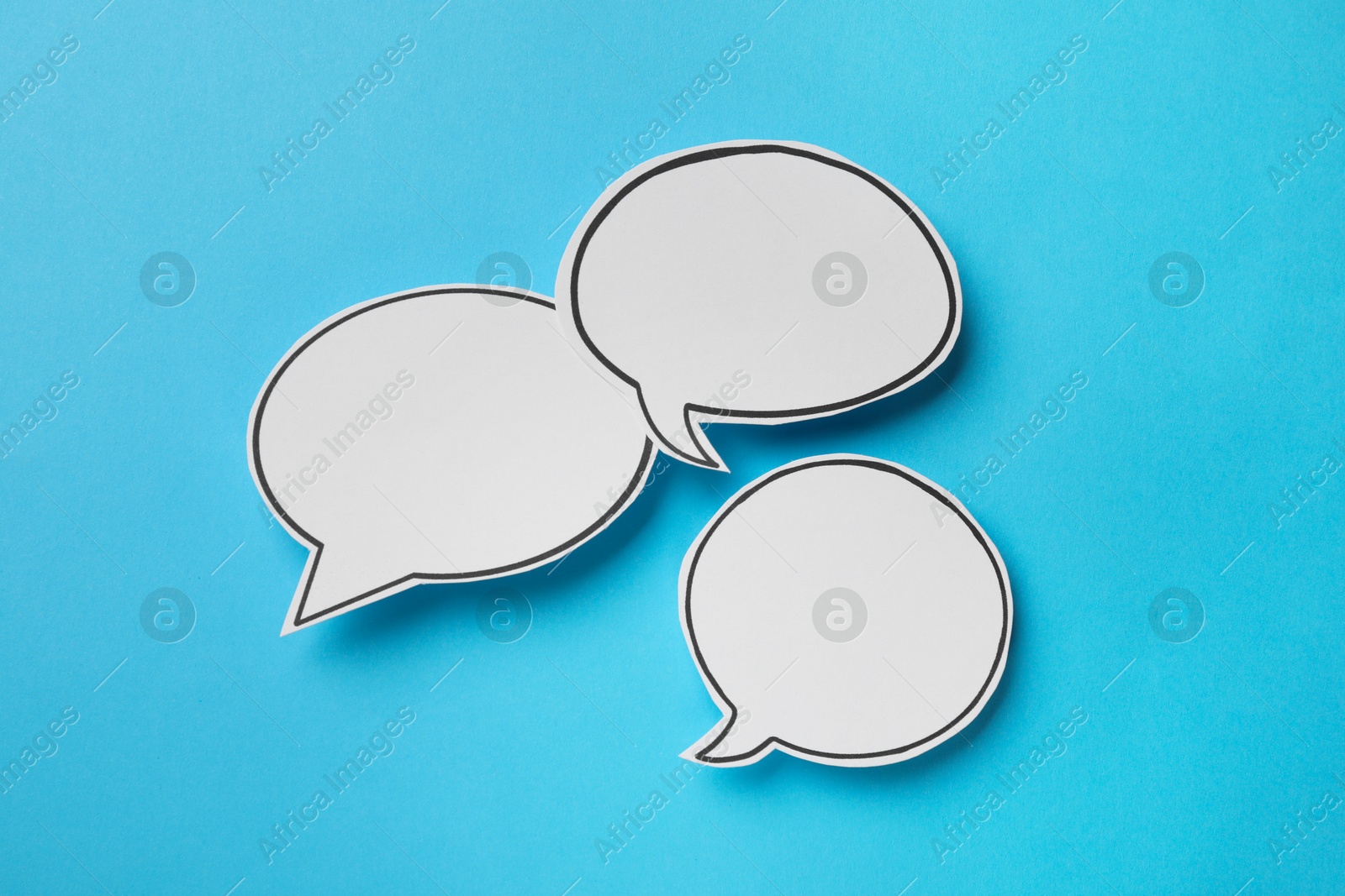 Photo of Blank speech bubbles on light blue background, top view. Space for text