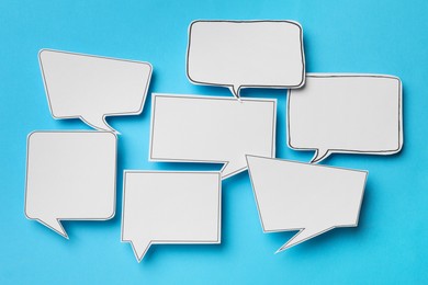 Photo of Blank speech bubbles on light blue background, top view. Space for text