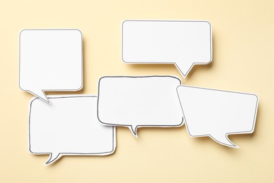 Photo of Blank speech bubbles on beige background, top view. Space for text