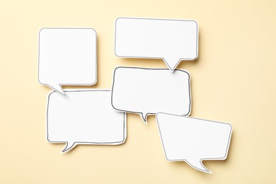 Photo of Blank speech bubbles on beige background, top view. Space for text