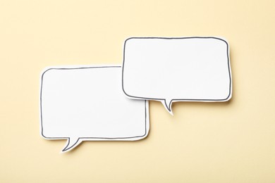 Photo of Blank speech bubbles on beige background, top view. Space for text