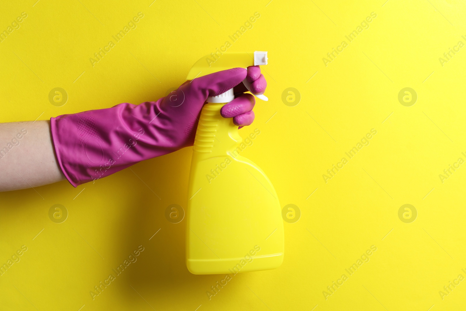 Photo of Woman with spray bottle of cleaning product on yellow background, closeup. Space for text