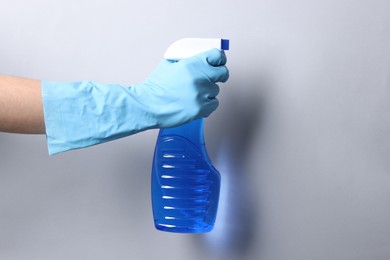 Photo of Woman with spray bottle of cleaning product on light grey background, closeup. Space for text