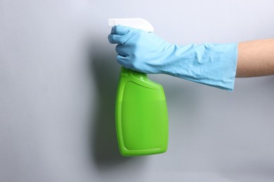 Photo of Woman with spray bottle of cleaning product on light grey background, closeup. Space for text