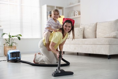 Photo of Little helper. Daughter and mother vacuuming together at home